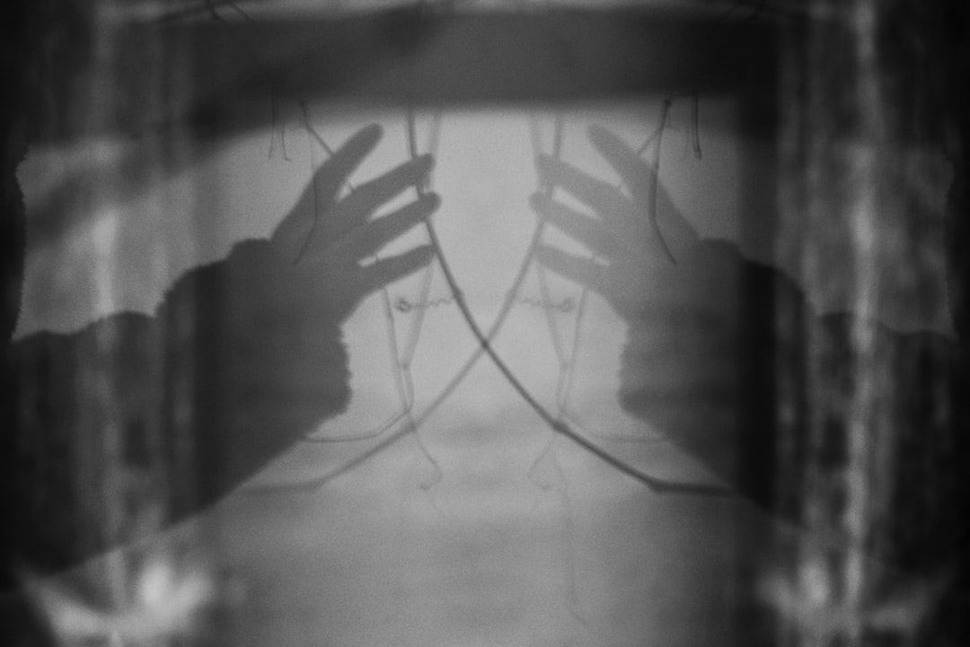 Close-up of philosopher's hands gesturing toward cracked mirror reflecting fragmented digital code, dramatic ambient lighting, abstract ideology concept, clean modern dark aesthetic