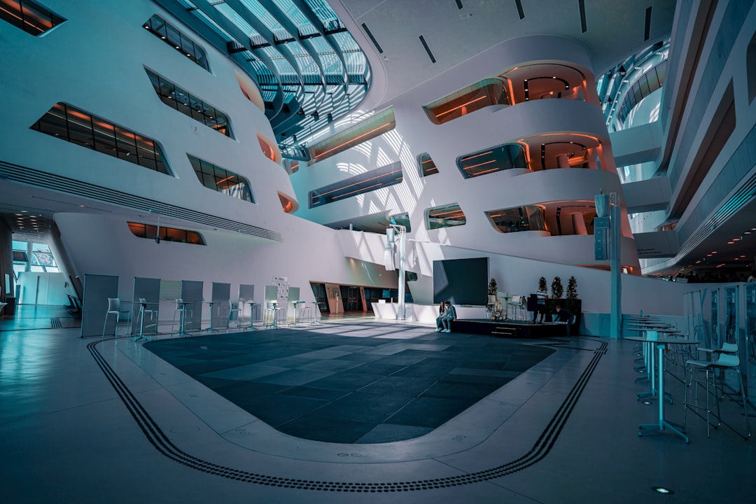 Futuristic government building interior with holographic data displays, suited professional observing neural network visualization, cool blue ambient lighting, sleek modern architecture, technology me