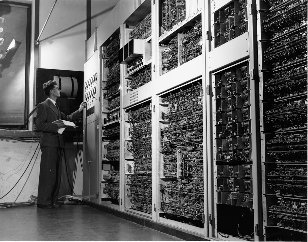 Historical timeline visualization merging vintage computing hardware with modern quantum server room, split-screen composition, warm to cool color gradient, human hands typing on holographic keyboard