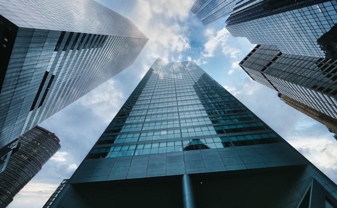 Split composition: corporate skyscraper reflecting storm clouds versus lean startup workspace, business crisis concept, dramatic contrast lighting, financial dashboard declining, sleek glass architect