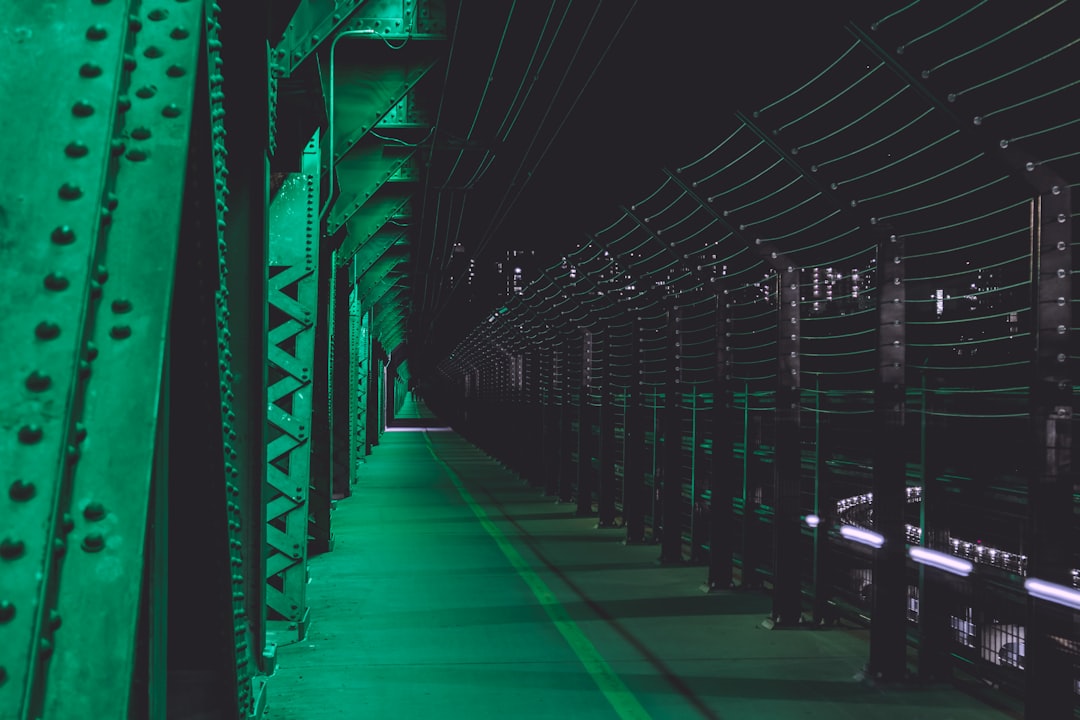 Massive hyperscale data center corridor stretching into darkness, rows of illuminated server racks with green LED indicators, single engineer in hard hat inspecting holographic infrastructure dashboar
