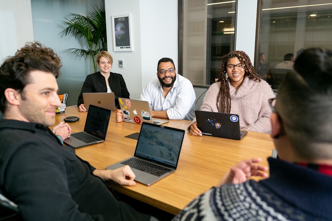 Diverse professional team collaborating around holographic financial dashboards showing cost reduction graphs, clean modern office with floor-to-ceiling windows, warm ambient lighting mixing with cool
