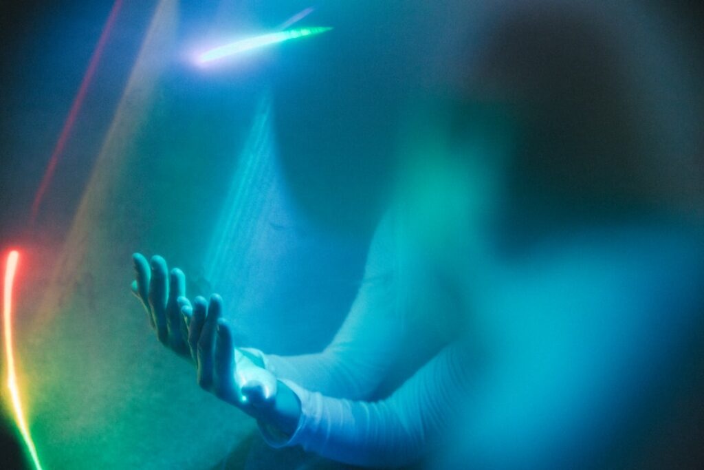 Futuristic robotic hand reaching toward human hand in sleek dark environment, blue ambient lighting, neural network hologram between them, symbolizing AI autonomy evolution