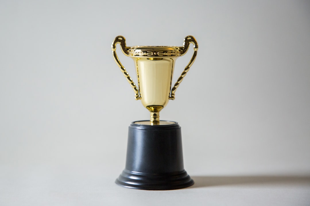 Prestigious golden trophy award on sleek glass pedestal with holographic neural network projection, futuristic dark museum lighting, professional editorial style, technology legacy concept