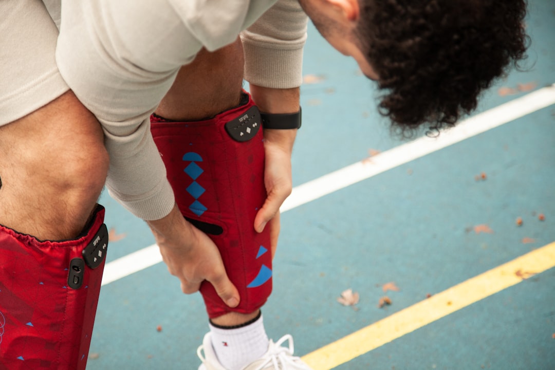 Close-up of athlete's muscular leg with wearable biometric sensors and medical AI interface displaying injury prediction data, sleek futuristic sports lab setting, soft ambient lighting, holographic a