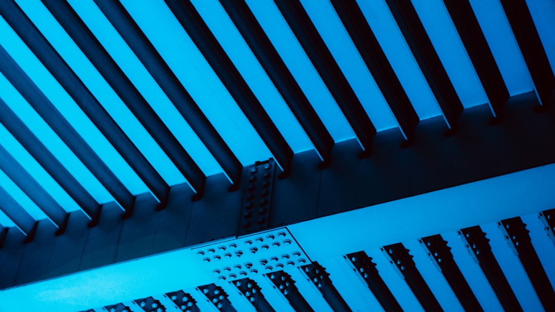 Sleek modern edge computing facility replacing massive data center, rows of compact modular servers with cool cyan ambient lighting, professional technician monitoring holographic dashboard, minimalis
