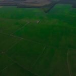 Futuristic drone scanning lush green crop fields at golden hour, holographic data overlay showing soil analytics, farmer with tablet, sleek ambient lighting, precision agriculture technology concept