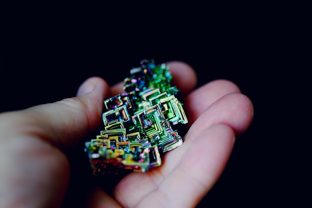 Human hand reaching toward glowing microchip with AI circuit pathways, abstract futuristic background, warm medal and green tones, innovation and ethics concept, sleek minimal composition
