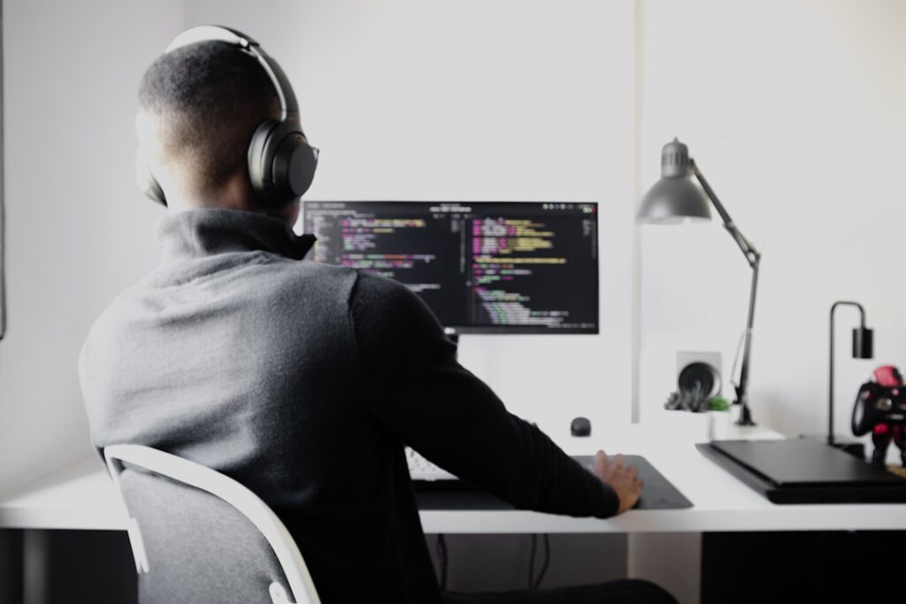Futuristic game developer wearing sleek AR glasses, holographic game engine interface floating in dark ambient room, neon blue neural network visualization, professional tech workspace