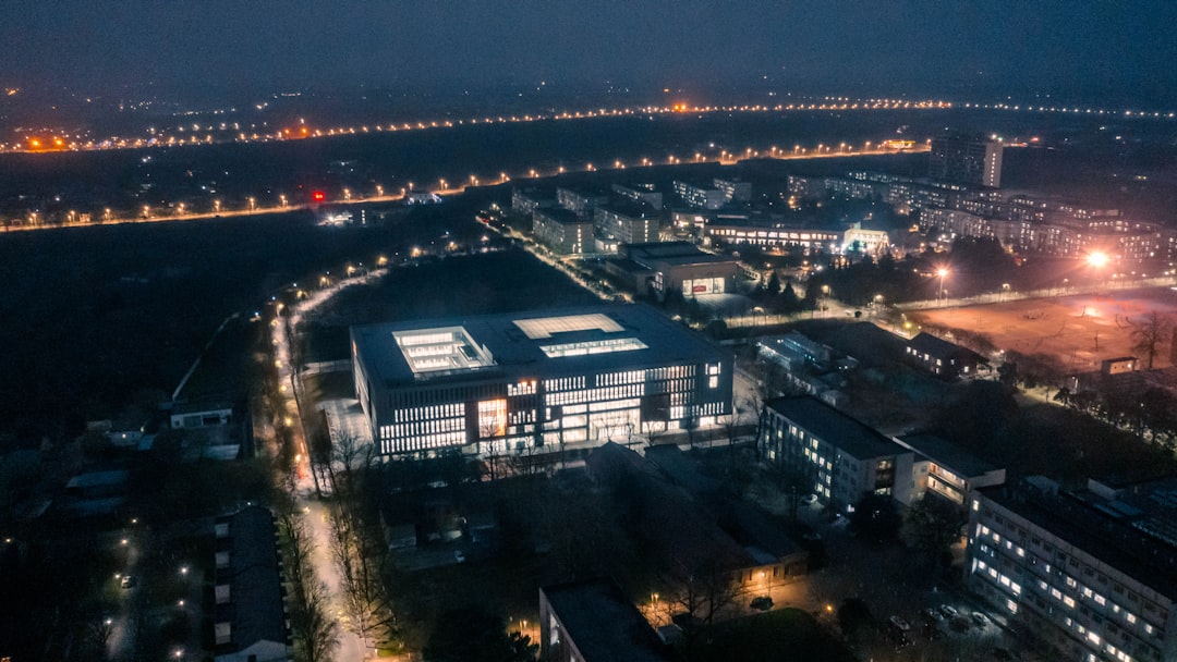 Aerial view of massive modern data center complex at dusk with glowing windows, surrounded by smart city infrastructure, financial graphs holographically projected, global economic growth visualizatio