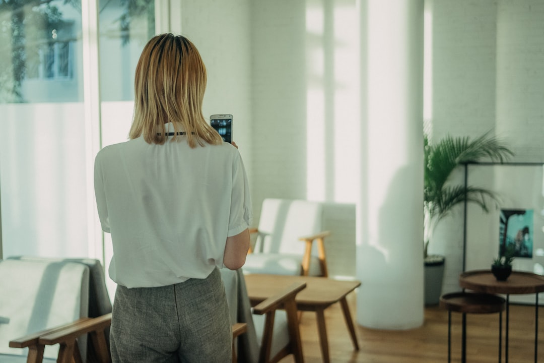 Professional woman in sleek clean modern office interacting with holographic display showing neural network visualization, futuristic ambient lighting blue tones, human-AI collaboration concept