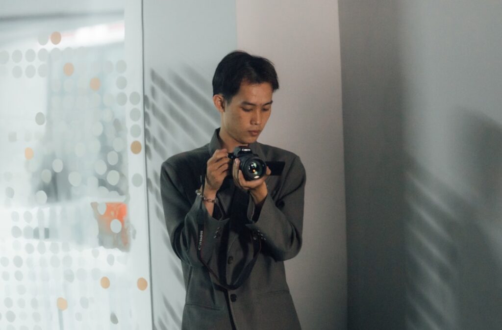 Professional photographer reviewing holographic camera interface with neural network overlays in sleek futuristic studio with ambient blue lighting