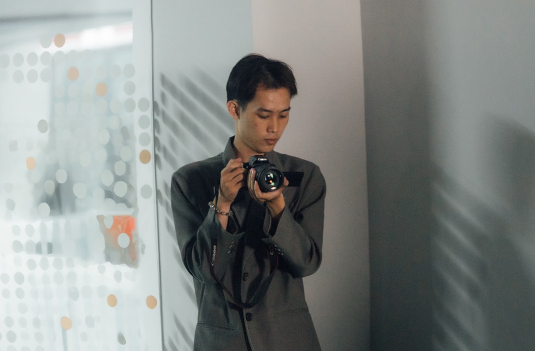 Professional photographer reviewing holographic camera interface with neural network overlays in sleek futuristic studio with ambient blue lighting