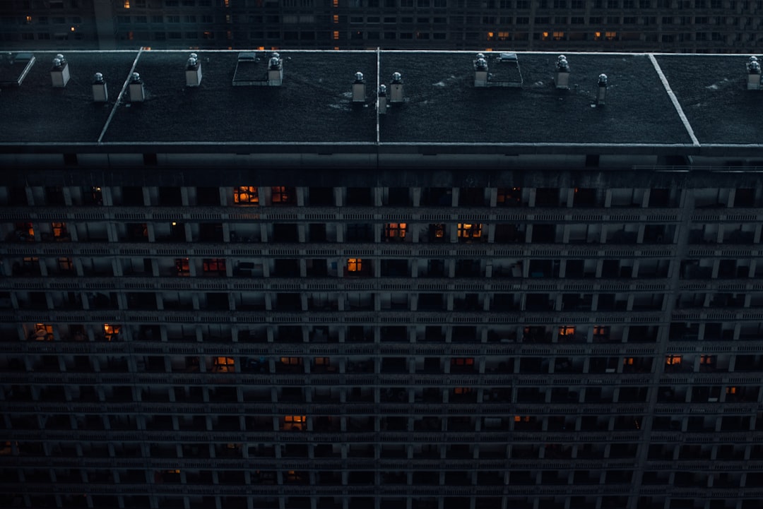 Aerial view of modern data center with server racks glowing blue, neural network visualization floating above, clean professional environment, ambient cool lighting, microchip detail in foreground