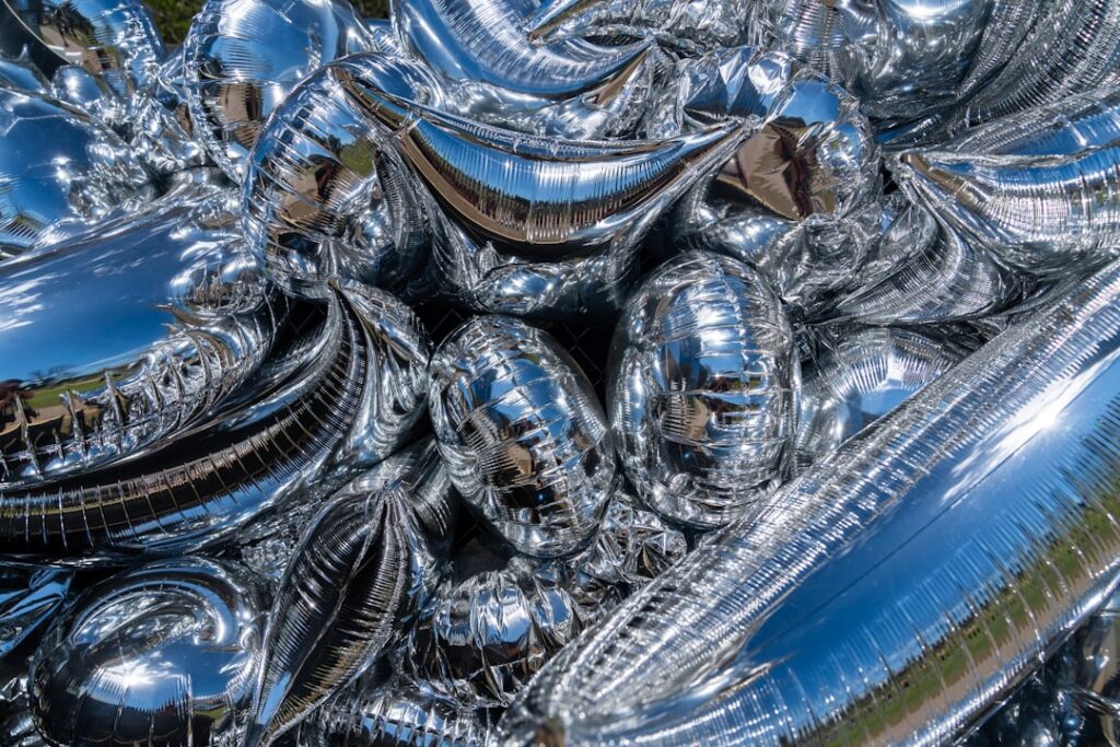 Deflated silver balloon with AI text symbol crumpled on sleek glass table, professional tech office with cool blue ambient lighting, blurred server room background, mood of disillusionment and realism