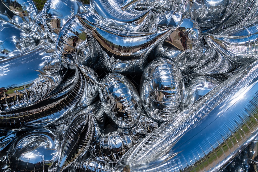 Deflated silver balloon with AI text symbol crumpled on sleek glass table, professional tech office with cool blue ambient lighting, blurred server room background, mood of disillusionment and realism