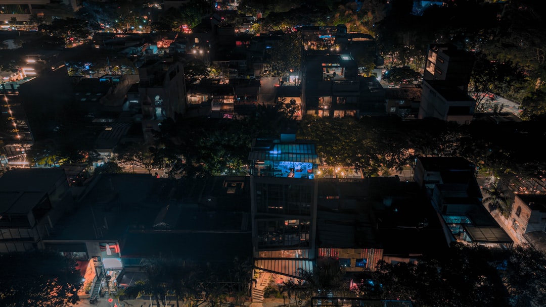 Aerial view of modern smart city at twilight with AI-powered surveillance network highlighted, clean streets, professional people walking safely, warm golden hour meets cool tech blue, futuristic urba