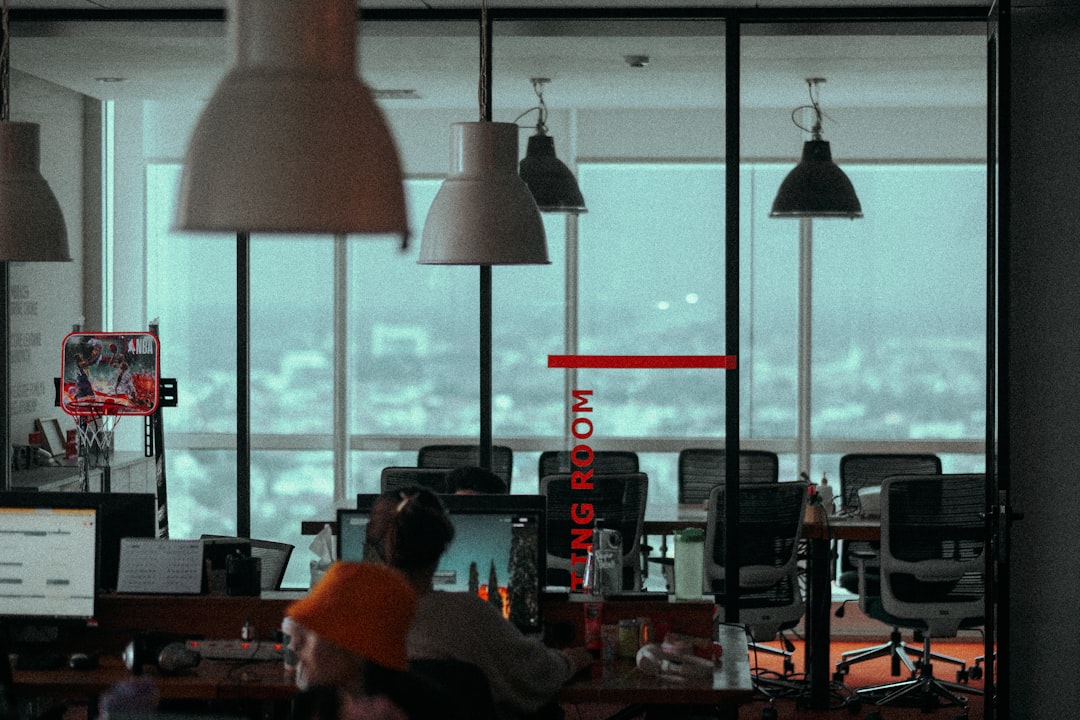 Clean modern office with transparent glass walls showing algorithm code projections, executive examining holographic data dashboard, cool professional lighting