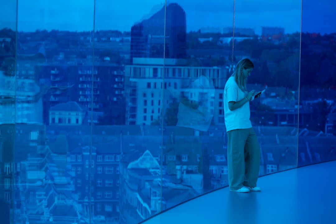 Professional architect reviewing AI-generated 3D building model on holographic display, clean modern office, cool blue ambient lighting, generative design algorithms floating as luminous particles