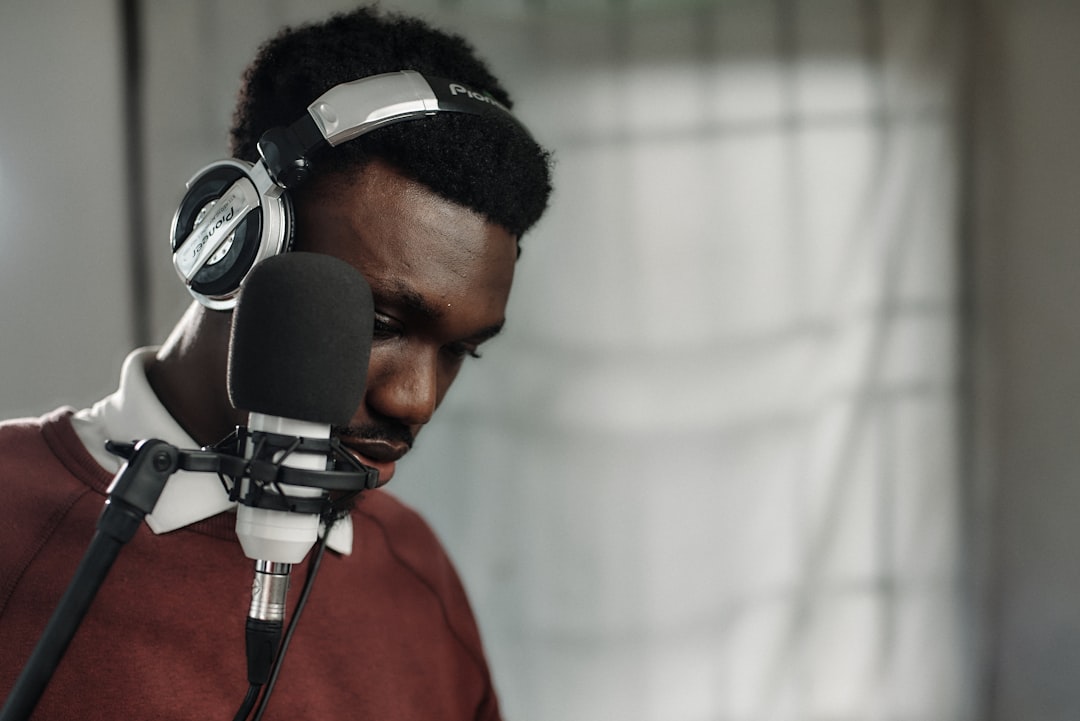 African music producer wearing sleek headphones interacts with holographic audio waveform display in futuristic Lagos studio, neon ambient lighting, data visualization overlays, professional tech envi