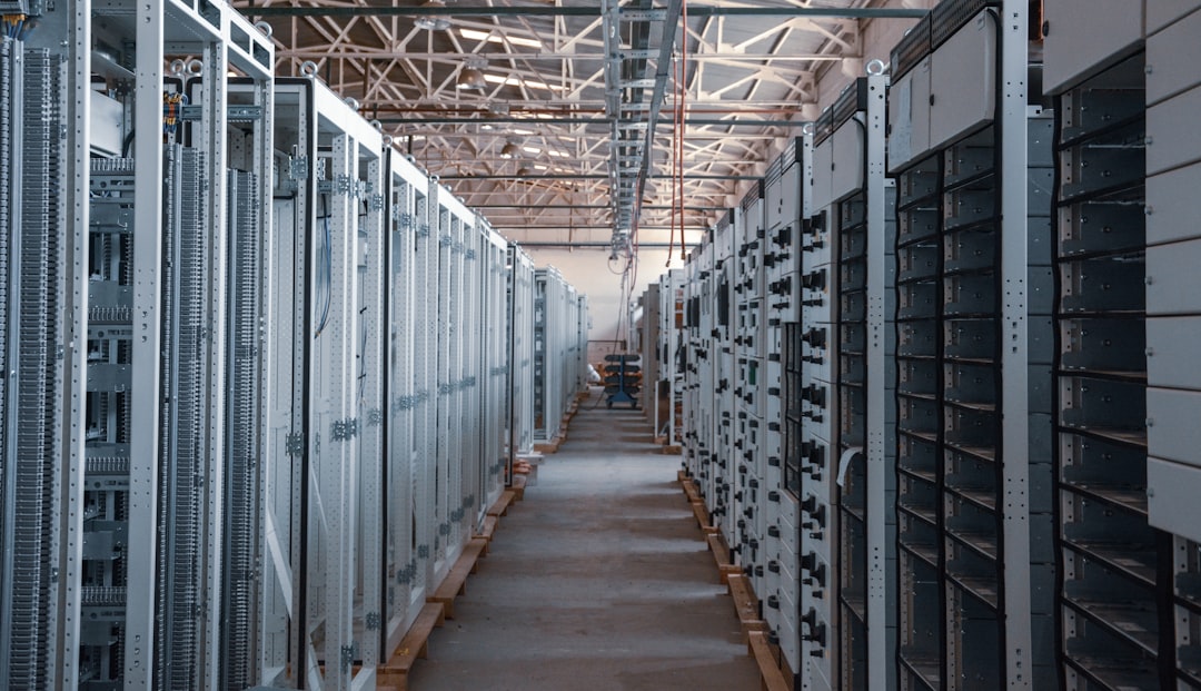 AWS server room corridor with ambient cyan and orange lighting, engineer examining holographic cloud architecture diagram, sleek data center with rows of glowing server racks, professional tech enviro