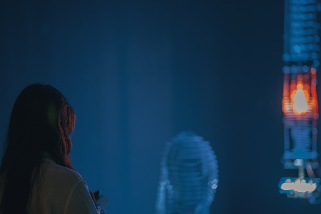 Scientist in clean modern office examining holographic display of neural network visualization, blue ambient lighting, futuristic data analysis, professional tech environment