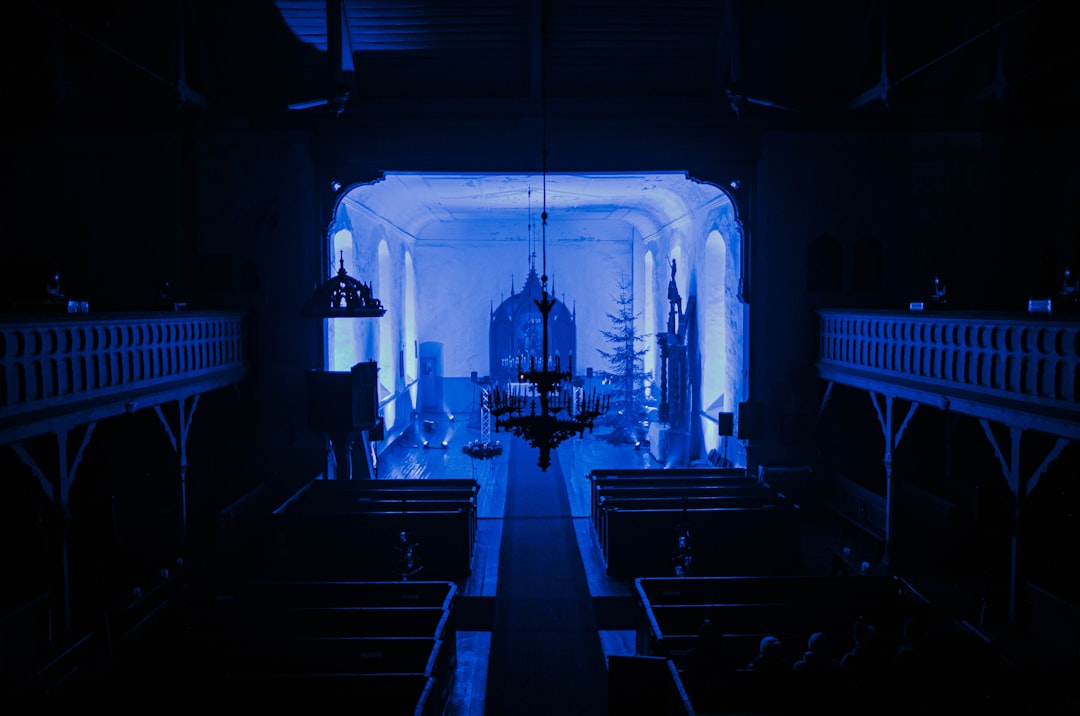 Futuristic church interior with holographic Bible projection, ambient blue lighting, pastor using sleek tablet, neural network visualization overlay, professional tech setting, human faith meets AI