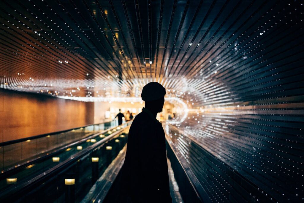 Futuristic executive silhouette facing holographic neural network display in sleek dark data center with blue ambient lighting and server racks