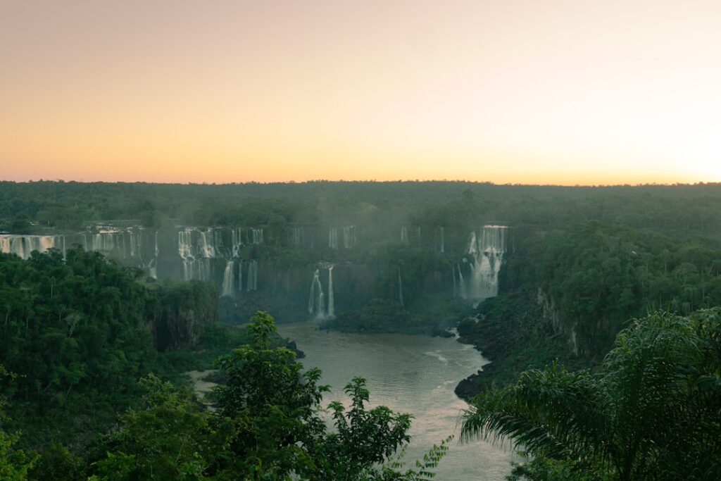 Futuristic aerial view of Foz do Iguacu waterfall at golden hour with holographic data overlays, diverse professionals in sleek conference setting, ambient teal and orange lighting, technology meets n