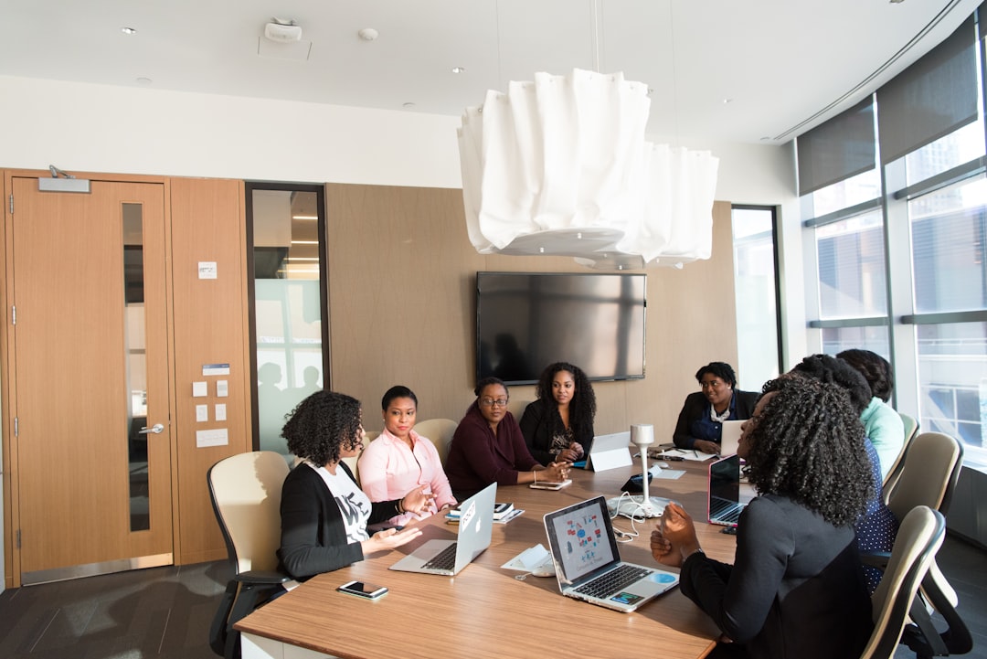 Diverse professional team gathered around holographic AI ethics visualization display, half illuminated by warm promise-glow half by cool risk-shadow, modern glass office with city skyline, contemplat
