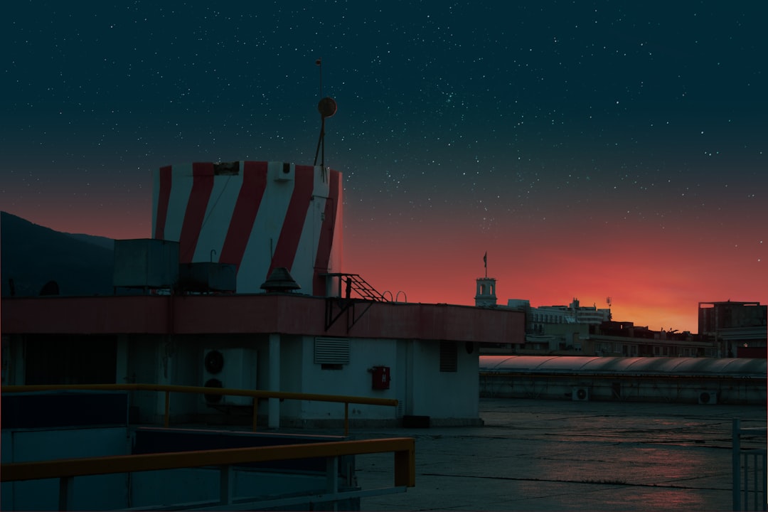 Sleek edge computing node installed on modern city rooftop at dusk, holographic data streams floating in air, professional engineer with tablet, ambient neon lighting, neural network visualization ove