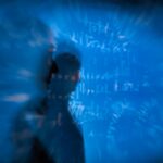 Futuristic financial analyst examining holographic AI stock projections on transparent screen, ambient blue lighting, clean modern office, data visualization overlays, professional investor using neur