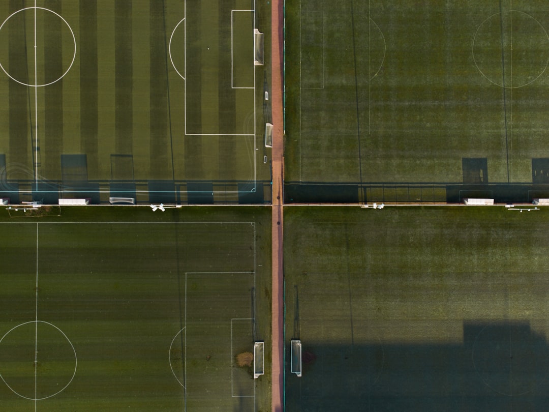 Futuristic soccer stadium merged with AI neural network visualization, holographic player analytics, professional coach with tablet, ambient stadium lighting, sleek data overlays on green pitch