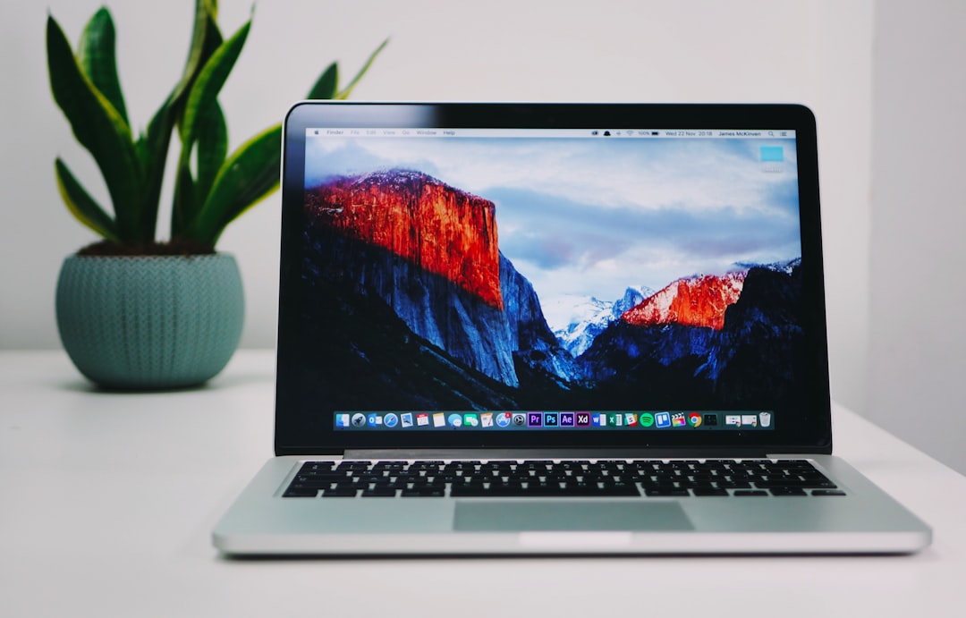 Sleek AI-powered laptop on minimalist desk with holographic chip architecture projection, neon circuit patterns, dark moody lighting, modern professional workspace, The Verge editorial style