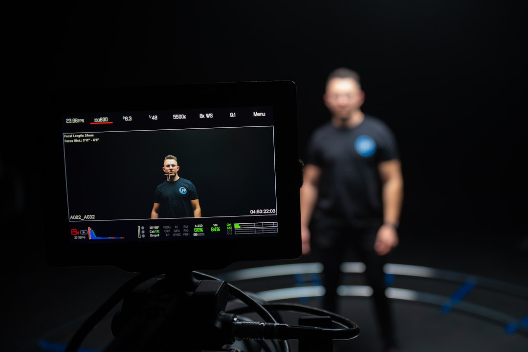 Sleek video recording studio with holographic display showing facial analysis metrics clean modern office with warm ambient lighting and diverse student presenter