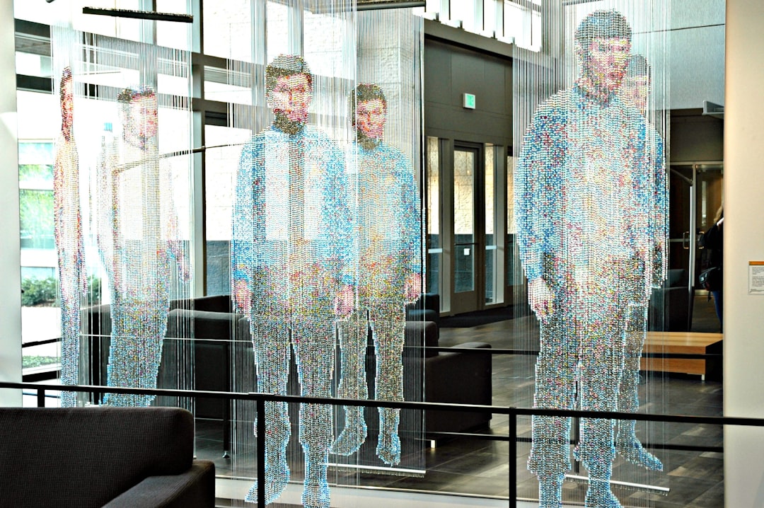 Autonomous AI agent as translucent humanoid figure in sleek modern office, multiple holographic screens displaying self-directed tasks, human worker observing passively, cool cyan and warm gold contra