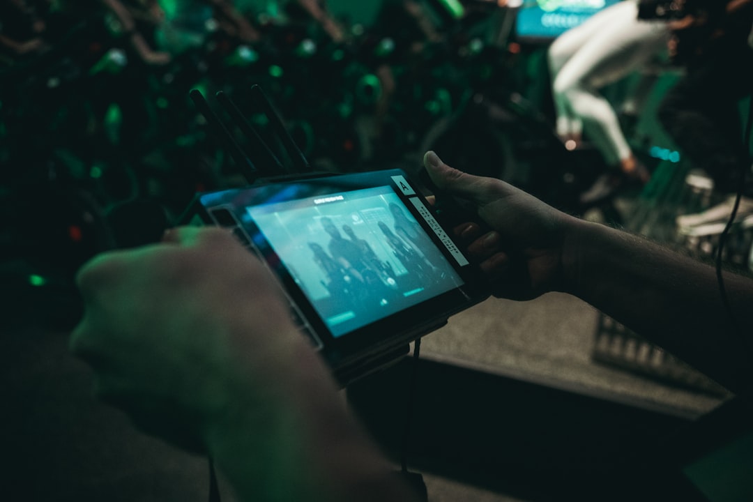 Athlete's hands holding a tablet displaying real-time performance analytics and neural network visualizations, sleek modern training facility, cool-toned ambient lighting, holographic football traject