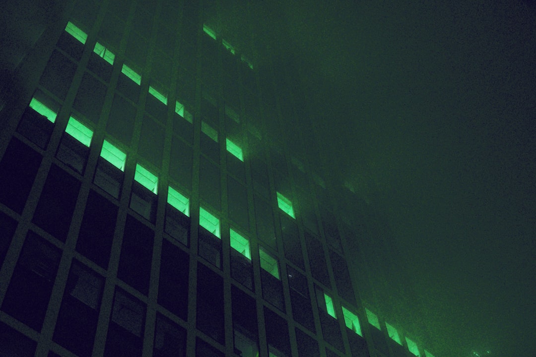 Crumbling corporate skyscraper hologram dissolving into digital particles, lone professional silhouette observing, dark moody ambient lighting, futuristic data center backdrop, teal and orange color g