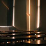 Futuristic classroom with holographic AI interface floating above sleek desks, ambient blue lighting, diverse students engaging with transparent screens, clean modern educational space
