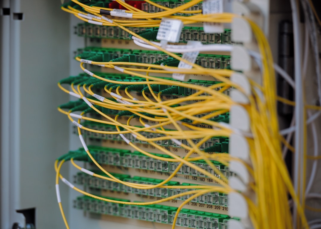 Massive data center server room with glowing neural network visualization overhead and exhausted technician examining energy consumption dashboard in dramatic green-red lighting