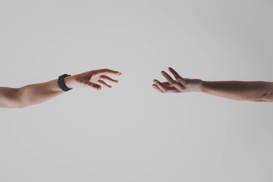 Close-up of human hand touching robotic hand on soccer ball, AI ethics concept, dramatic split lighting warm and cool tones, professional studio setting, human-machine collaboration