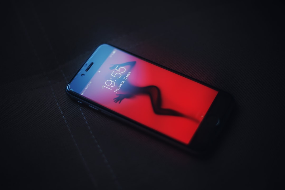 Smartphone with pulsing red alert on wellness app interface, anxious user silhouette in background, clean modern office setting, data privacy warning symbols floating